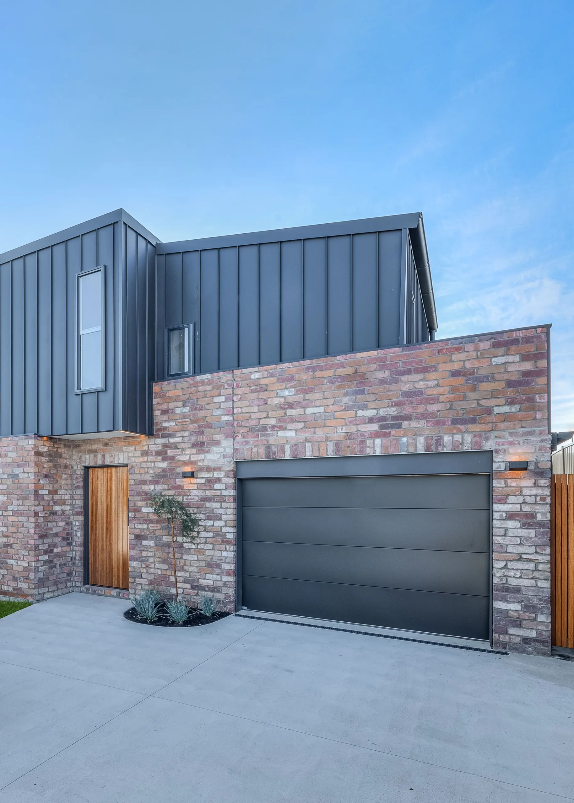 house with recycled brick walls with black garage doors and wall cladding